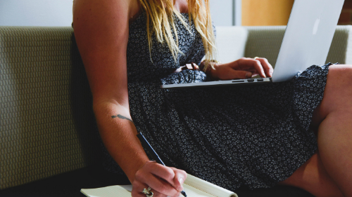 A woman using her laptop and taking notes