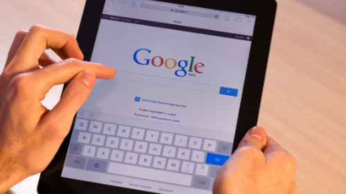 Person holding a tablet to search on Google