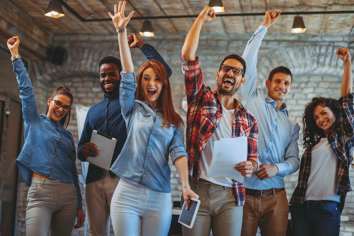 Group of company employees celebrating with their fists pumped in the aire